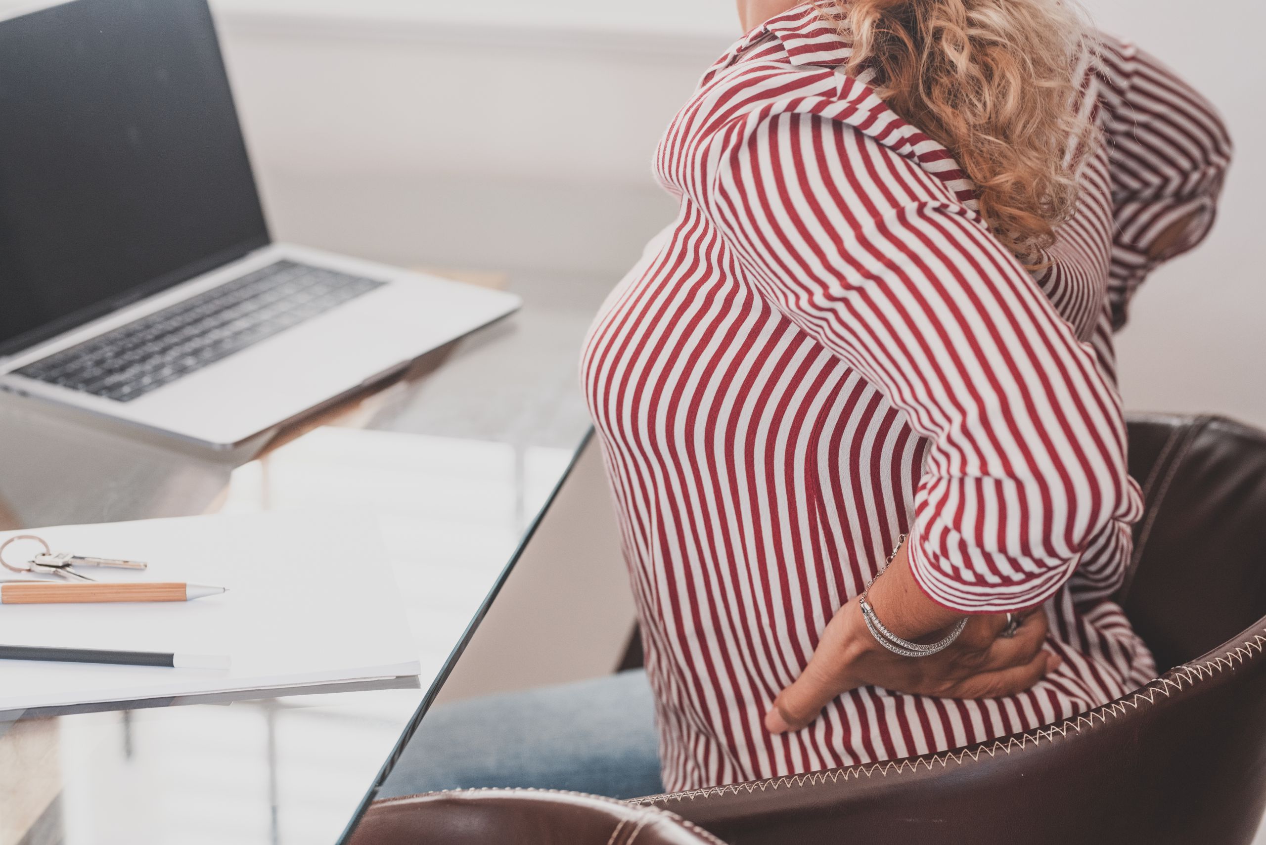 Close up rear view stressed young woman touching lower back feeling discomfort, suffering from sudden pain due to sedentary lifestyle or long computer overwork in incorrect posture at home office. Weight management probiotics